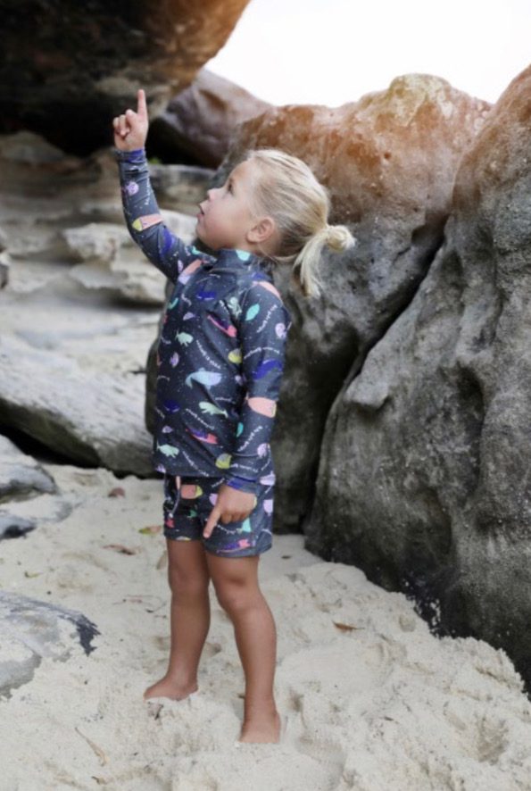 Little Girl Wearing a Swim Shirt and Shorts standing on the beach