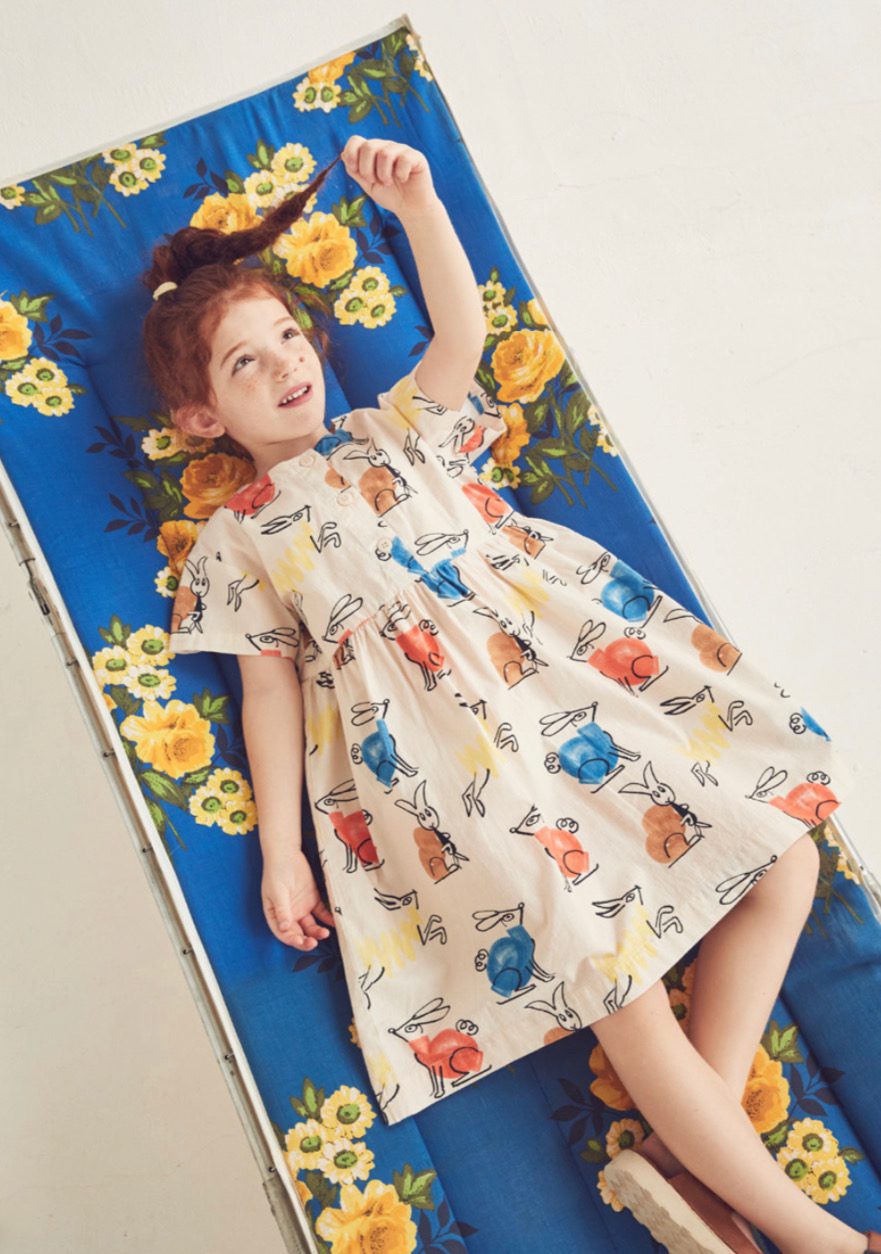 Little Girl Wearing a Dress With Bunnies on It while laying on a beach mat